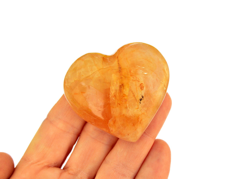 One small golden healer quartz heart 50mm on hand with white background