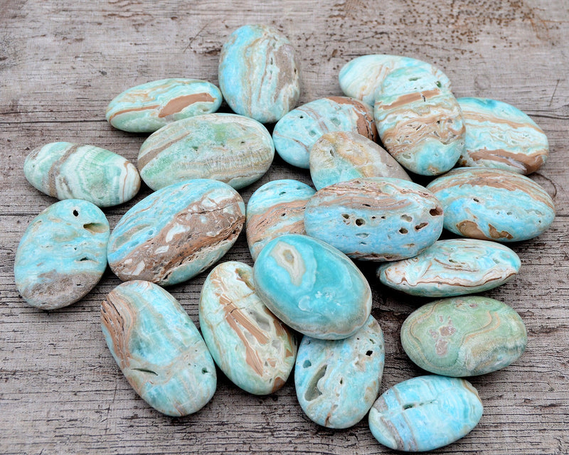 Several blue aragonite palm stones on wood table