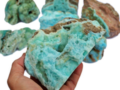 Raw blue aragonite large specimen on hand with background with some stones on white