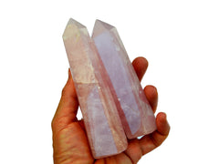 Two pink quartz tower crystals on hand with white background