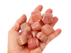 Ten rose calcite tumbled stones on hand with white background