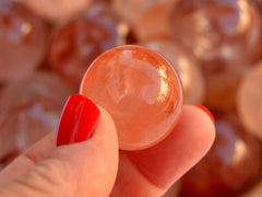 One hematoid quartz crystal sphere stone 25mm on hand with background with several spheres 