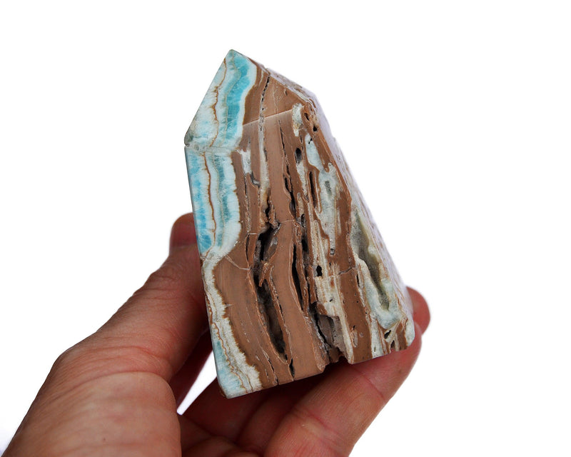 One druzy blue aragonite crystal tower on hand with wood background