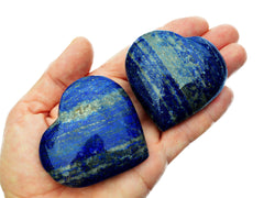 Two lapis lazuli heart shaped crystals 60mm-65mm on hand with white background