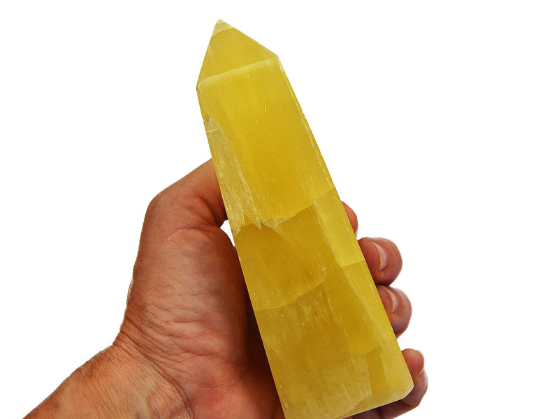 One lemon calcite crystal obelisks 150mm on hand with white background