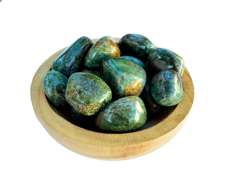 Several large green chrysocolla tumbled minerals inside a wood bowl on white background