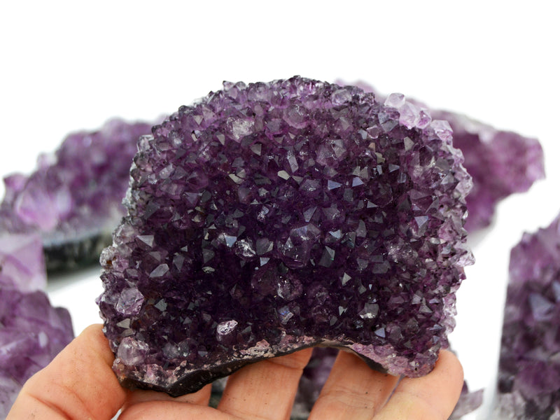 Amethyst crystal held in a hand with a blurred background with some crystals