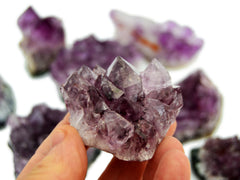 One amethyst druzy crystal 40mm on hand with background with some stones on white