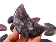 One purple lepidolite moon stone 90mm on hand with background with some specimens on white