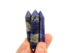 Three small faceted lapis lazuli points 55mm on hand with white background