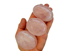 Three pink quartz palmstones 55mm on hand with white background