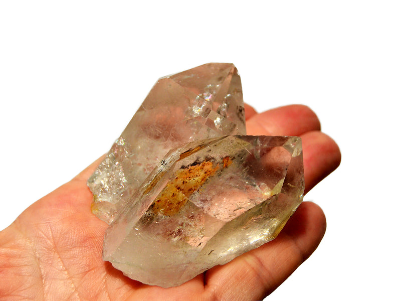Double clear rock crystal point held in a hand against a white background