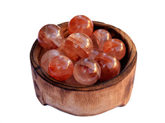 Several fire quartz crystal spheres 25mm-40mm inside a wood bowl on white background