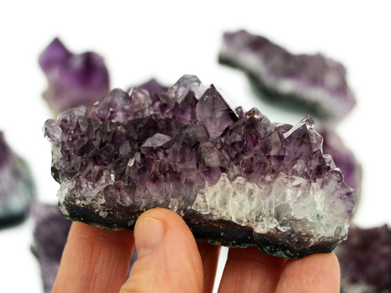 One brazilian druzy amethyst crystal 110mm on hand with background with some stones on white