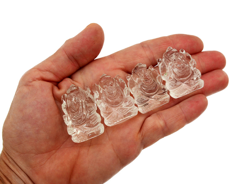 Four mini clear quartz crystal ganesha sculptures 30mm on hand with white background