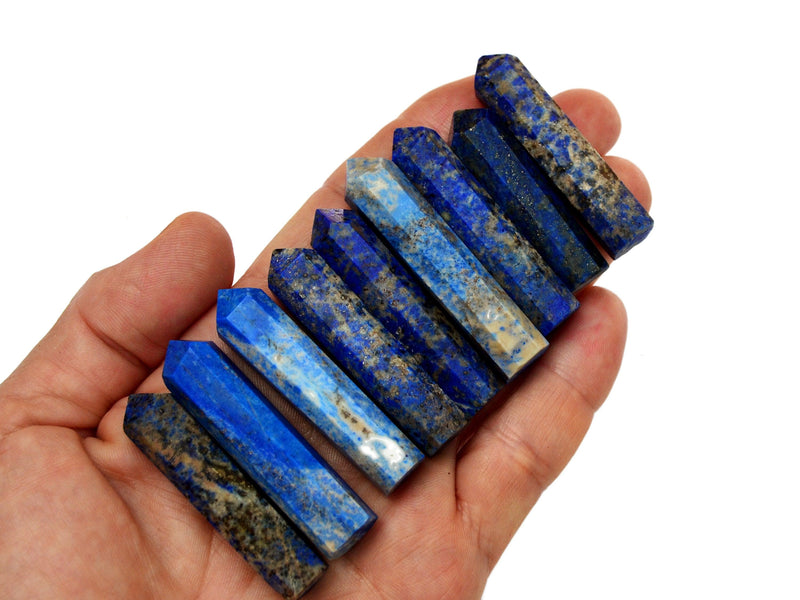 Nine lapis lazuli faceted crystals points 40mm-50mm on hand with white background