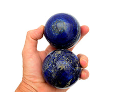 Three lapis lazuli sphere stones 65mm-70mm on hand with white background