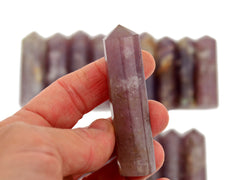 One lepidolite crystal generator 60mm on hand with background with some points on white