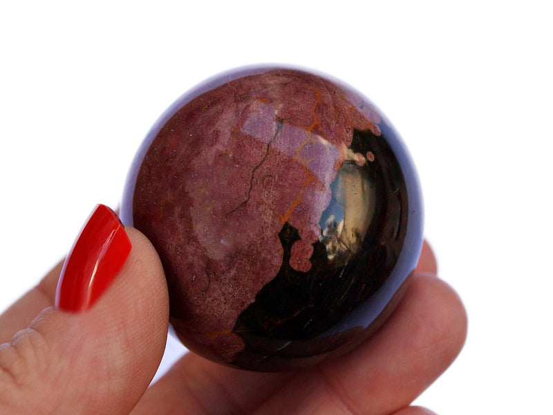 One pink ocean jasper crystal sphere 45mm  on hand with white background