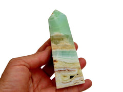 One green pistachio calcite tower 125mm on hand with white background 