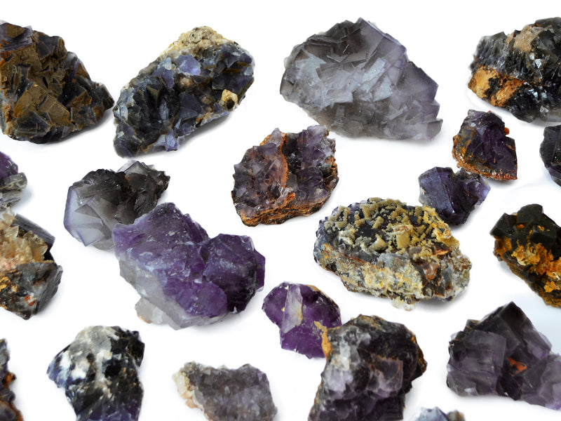 Several raw purple fluorite crystal clusters on white background