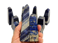 Two lapis lazuli tower stones on hand with some crystals on white background