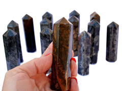 One ocean jasper tower crystal 90mm on hand with background with some obelisks on white