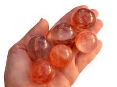 Six small fire quartz sphere stones 30mm - 35mm on hand with white background