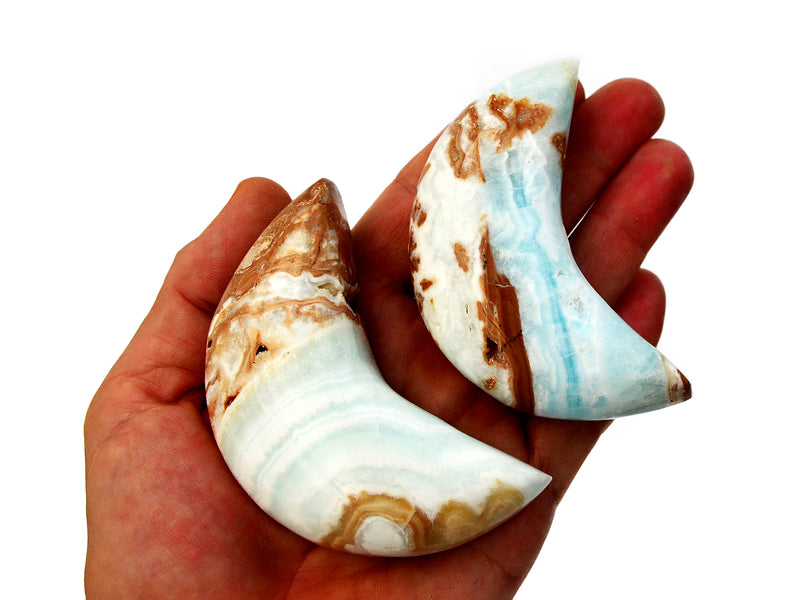 Two caribbean calcite shapped moon stones 75mm on hand with white background