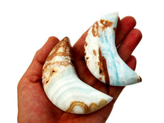Two caribbean calcite shapped moon stones 75mm on hand with white background
