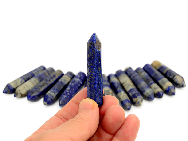 One faceted lapis lazuli point 55mm on hand with background with some prisms on white