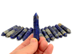 One faceted lapis lazuli point 55mm on hand with background with some prisms on white