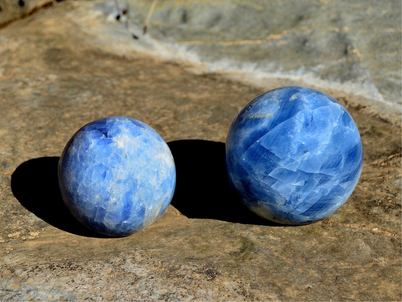 Two big blue calcite crystal balls on natural rock