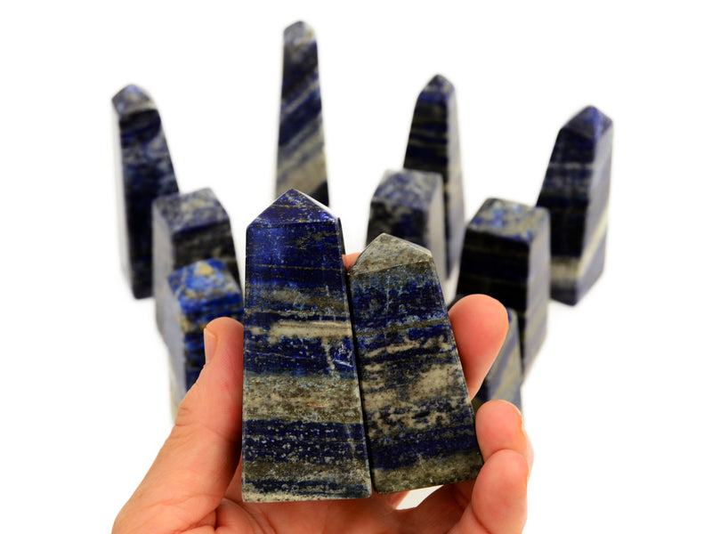 Two lapis lazuli towers on hand with some crystals on white background