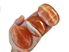 Three honey calcite palm stones 70mm-85mm on hand with white background
