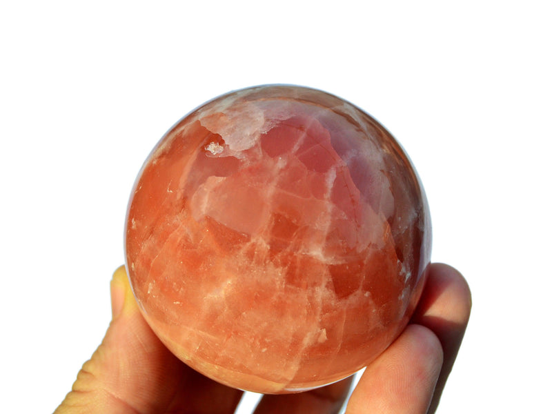 One rose calcite sphere stone 60mm on hand with white background