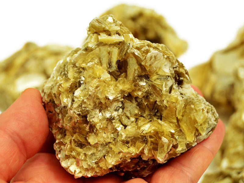 One large muscovite raw crystal 90mm on hand with background with some stones on white