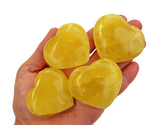 Four lemon calcite heart minerals 50mm-65mm on hand with white background