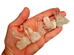 Five mini clear quartz clusters 30mm on hand with white background