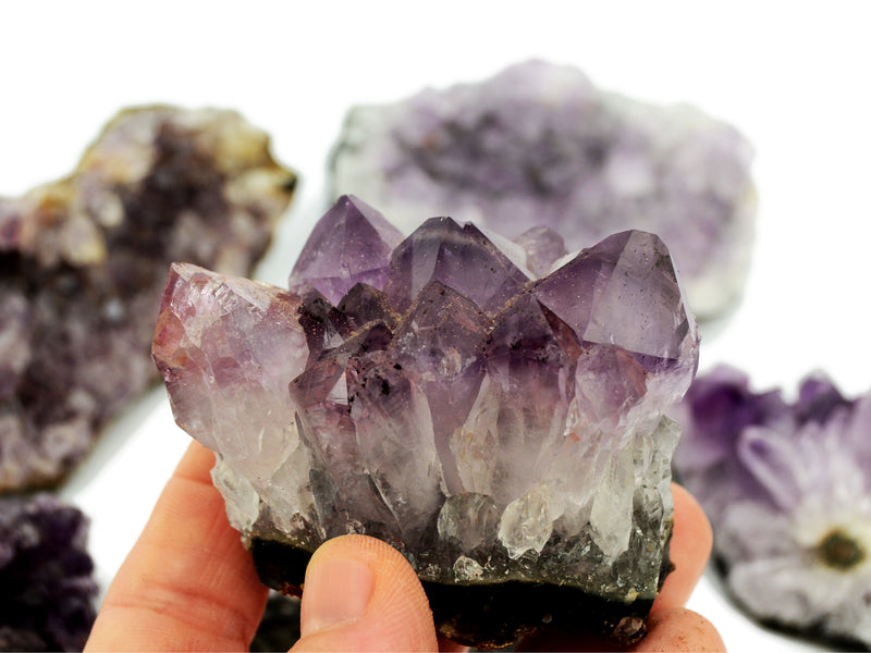 One druzy amethyst 70mm on hand with background with some stones on white