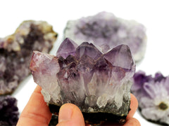 One druzy amethyst 70mm on hand with background with some stones on white