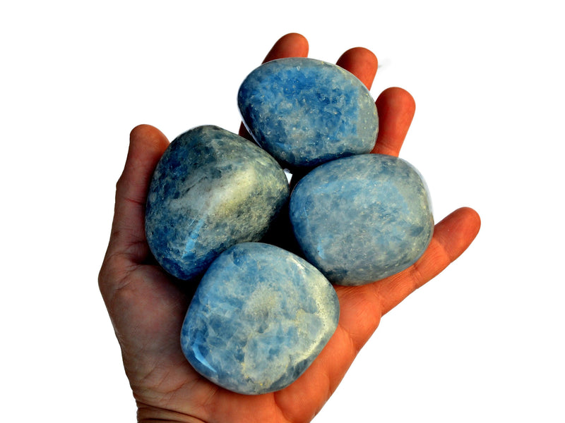 Four big blue calcite tumbled stones on hand with white background
