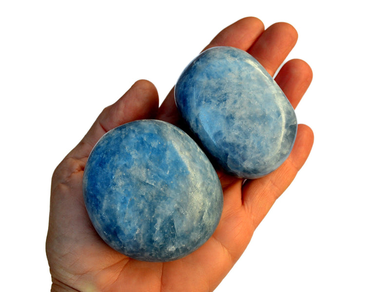 Two large blue calcite tumbled stones on hand with white background
