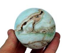 One large caribbean blue calcite sphere 65mm on hand with white background