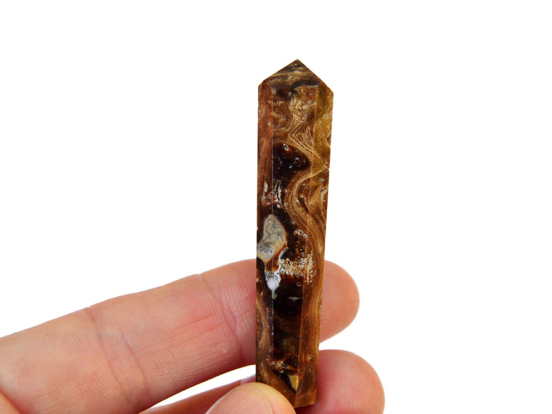 One caramel chocolate calcite faceted point mineral 55mm on hand with white background