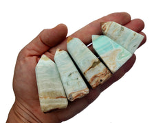Five small caribbean calcite crystal obelisks on hand with white background
