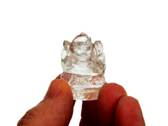 Reverse of one mini clear quartz ganesha sculpture 30mm on hand with white background