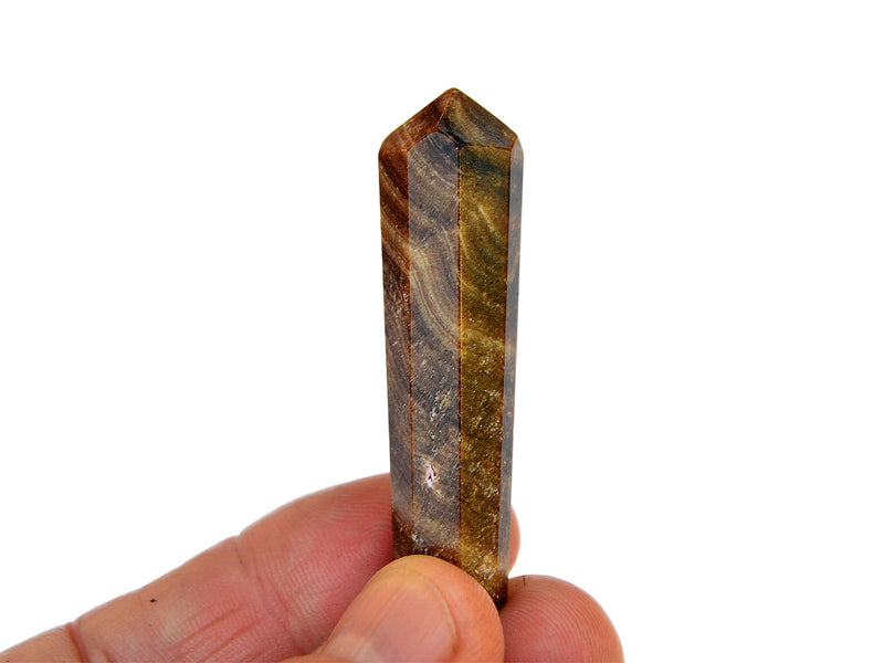 One caramel calcite faceted point mineral 50mm on hand with white background