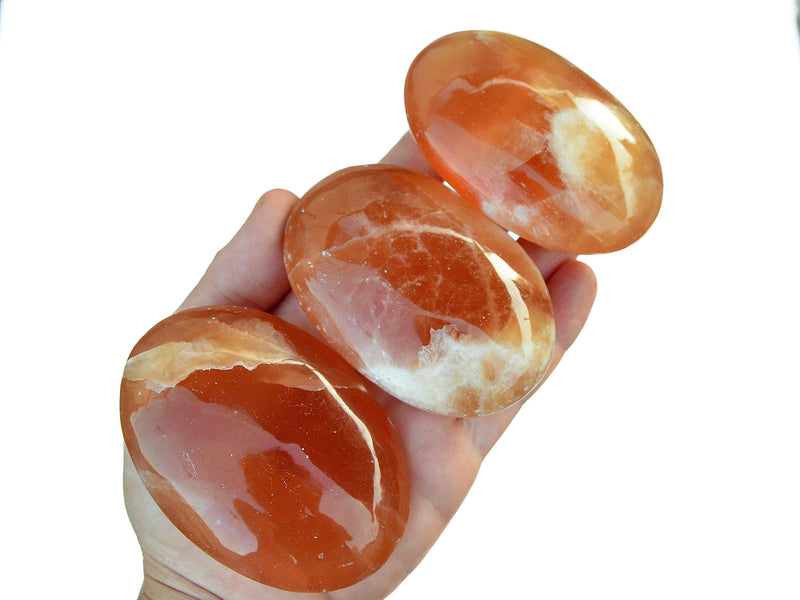 Three natural honey calcite palm stones 80mm-85mm on hand with white background