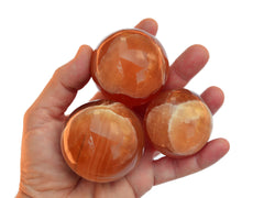 Three honey calcite crystal spheres 55mm on hand with white background